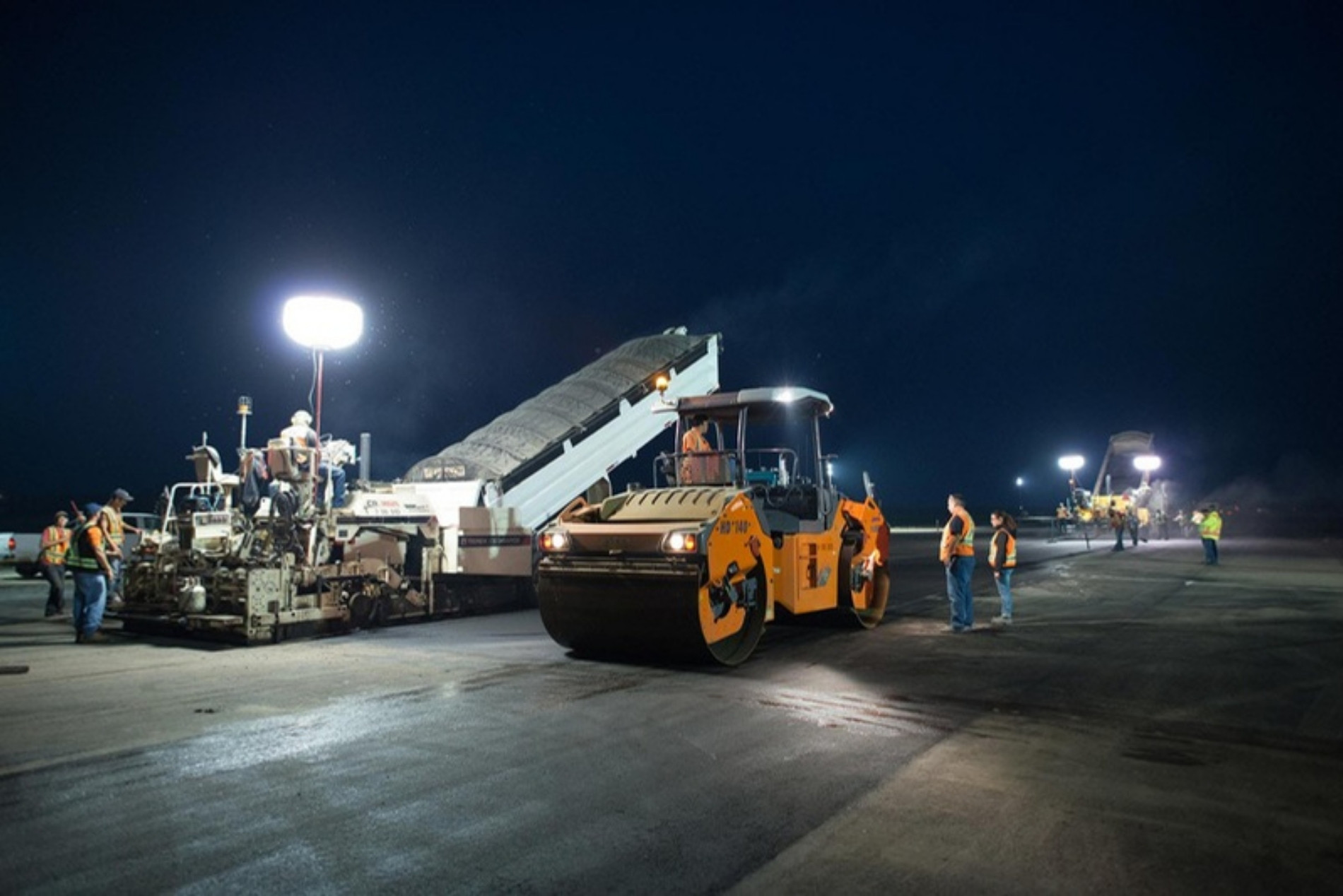 Night roadway paving with a paver and roller